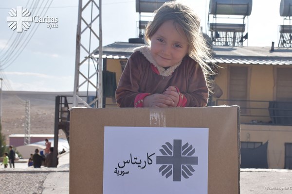 Ein Mädchen mit einem Karton mit Hilfsgütern der Caritas. Auch nach dem Ende der meisten Kampfhandlungen sind die Menschen in Syrien auf Hilfe zum Überleben angewiesen.